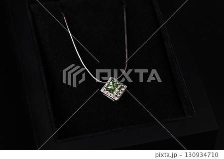 A green gemstone pendant is displayed on a black background 130934710