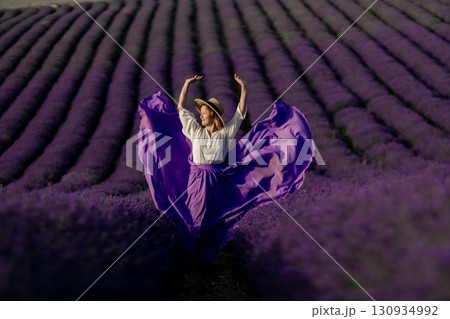 A woman in a purple skirt is dancing in a field of lavender A woman in a purple skirt is dancing in a field of lavender 130934992