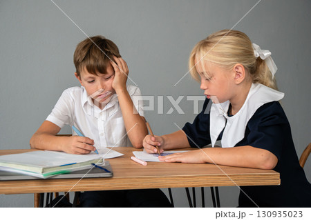 Children School Homework Study - Two children in school uniforms sitting at a desk doing homework. 130935023