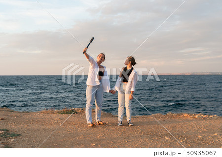 Couple Beach Selfie Sunset - Two people take a selfie on a beach at sunset. Couple Beach Selfie Sunset - Two people take a selfie on a beach at sunset. 130935067