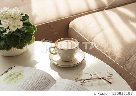 Cozy Living Room with Coffee, Book and African Violet on Table Cozy Living Room with Coffee, Book and African Violet on Table 130935195