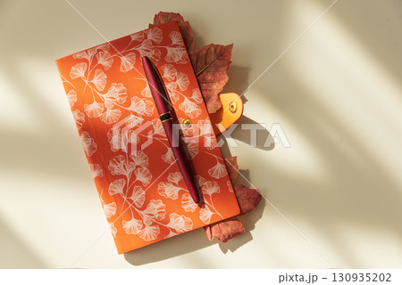 Autumn Notebook with Leaves and Pen on Light Background under Sun light Autumn Notebook with Leaves and Pen on Light Background under Sun light 130935202