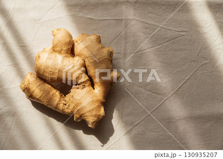 Fresh Ginger Roots on Light Fabric Background with Soft Natural Light Fresh Ginger Roots on Light Fabric Background with Soft Natural Light 130935207