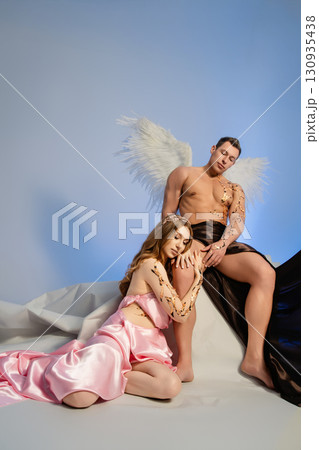 Couple embracing in elegant attire with angelic theme and soft background 130935438