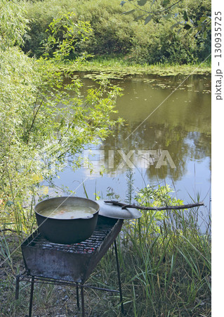 Soup is cooked in pot near the river. Cooking in nature. Cooked food 130935725