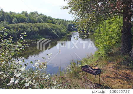 Cooking meat on river bank. Frying pieces of meat. Delicious dish fried on pan 130935727