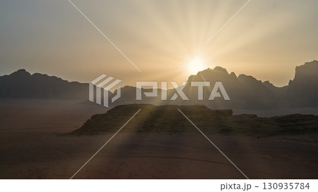 Sunrise over a serene desert landscape with mountains in the distance 130935784
