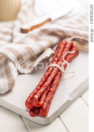 Smoked kabanos. Mini dried thin sausages on cutting board. Smoked kabanos. Mini dried thin sausages on cutting board. 130936120