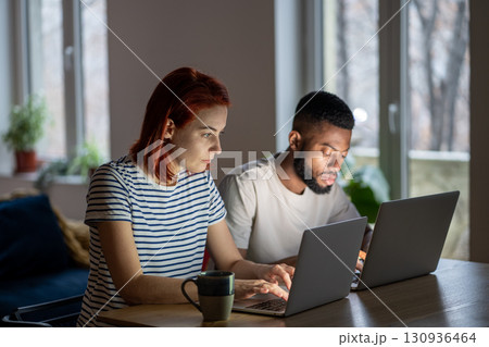 Focused entrepreneurs caucasian woman african american man work on laptops in home office together. 130936464