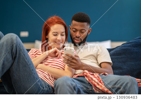 Guy and girl hug using phone. Woman and man watching videos, news from smartphone, smiling, laughing Guy and girl hug using phone. Woman and man watching videos, news from smartphone, smiling, laughing 130936483