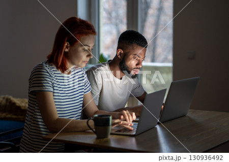Serious black man and woman working on laptops. Focused remote workers concentrate on online working 130936492
