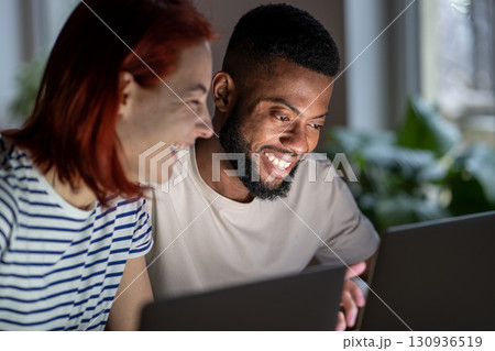Happy man woman freelancers discussing project working on laptops looking at screen. 130936519