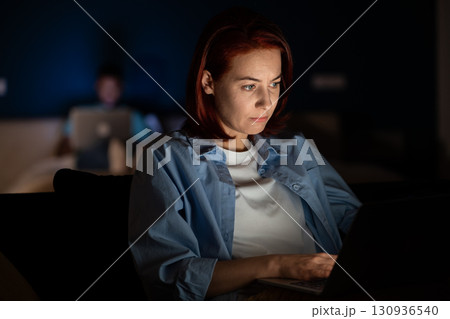 Woman uses laptop, works, studies. Overwork until late in evening, fatigue, hard study 130936540
