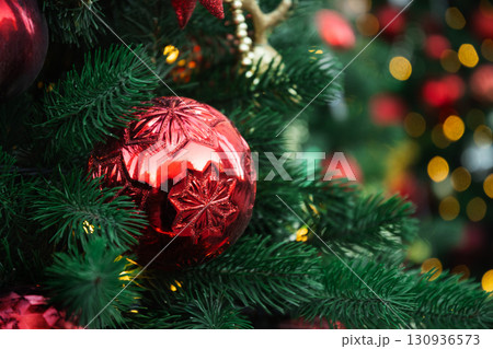 Christmas tree with red ball and lights garland. Xmas card. Close up. Winter holiday spirit. Outdoors. Christmas tree with red ball and lights garland. Xmas card. Close up. Winter holiday spirit. Outdoors. 130936573