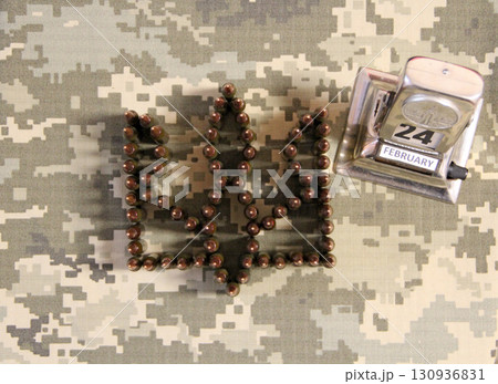 Coat of arms of Ukraine laid out from cartridges on camouflage clothing Coat of arms of Ukraine laid out from cartridges on camouflage clothing 130936831
