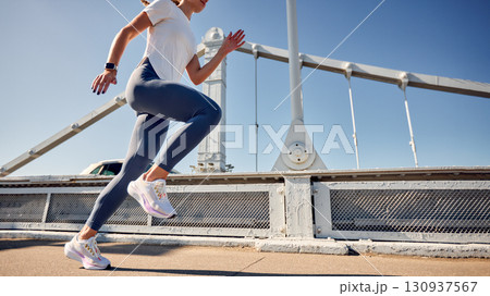 Woman running on a bridge during a sunny day with modern athletic shoes 130937567