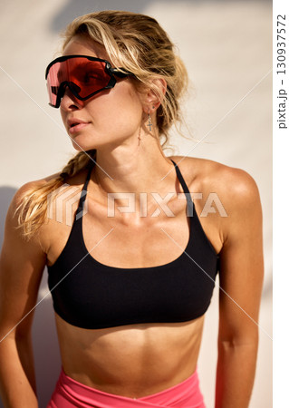 Woman with athletic attire and goggles posing outdoors in natural lighting 130937572
