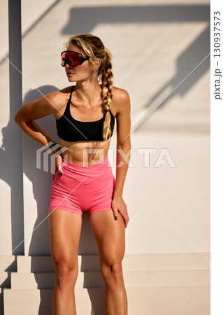 Woman in athletic wear outdoors posing under sunlight Woman in athletic wear outdoors posing under sunlight 130937573