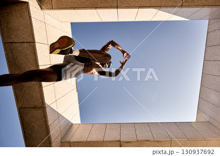 Dynamic low-angle shot of a sporty man leaping in urban architecture 130937692