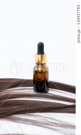 Hair treatment serum bottle positioned on smooth hair strands, showcasing a nourishing solution for split ends and promoting healthy hair care 130937765