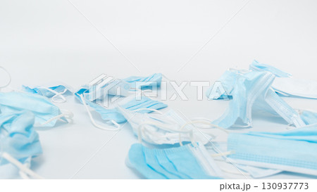 Discarded medical face masks scattered on a clean surface, showcasing various shades of blue and white, emphasizing the environmental impact of single-use protective equipment in healthcare settings Discarded medical face masks scattered on a clean surface, showcasing various shades of blue and white, emphasizing the environmental impact of single-use protective equipment in healthcare settings 130937773