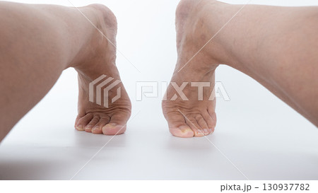 Close-up view of two bare feet positioned apart on a smooth surface, showcasing natural skin texture and relaxed posture in a serene setting Close-up view of two bare feet positioned apart on a smooth surface, showcasing natural skin texture and relaxed posture in a serene setting 130937782