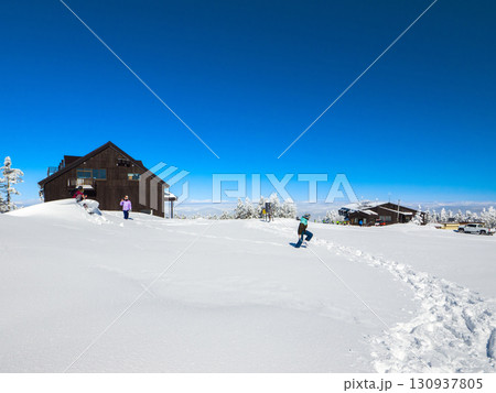 横手山山頂のリフト駅舎と新雪で遊ぶ若者たち (長野県、山ノ内町、横手山) 130937805