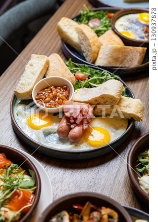 Traditional English breakfast with eggs, sausages, beans, bacon, and fresh bread on plate Traditional English breakfast with eggs, sausages, beans, bacon, and fresh bread on plate 130937878