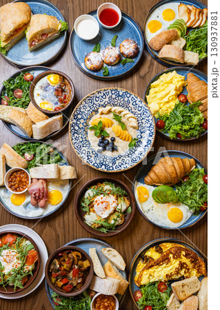 Assorted gourmet breakfast dishes on a rustic wooden table, top view Assorted gourmet breakfast dishes on a rustic wooden table, top view 130937881