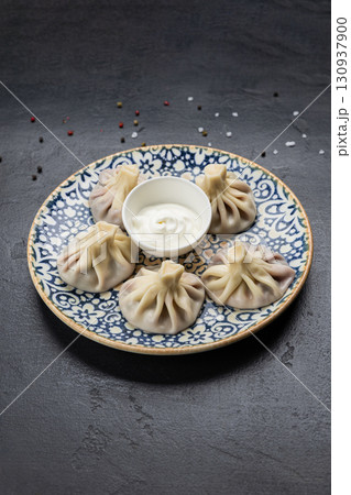 Traditional Georgian khinkali dumplings with sour cream sauce on ceramic plate Traditional Georgian khinkali dumplings with sour cream sauce on ceramic plate 130937900