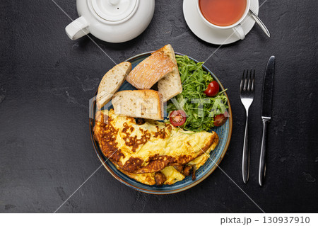 Healthy breakfast with omelet, ciabatta, salad and tea on dark stone background Healthy breakfast with omelet, ciabatta, salad and tea on dark stone background 130937910