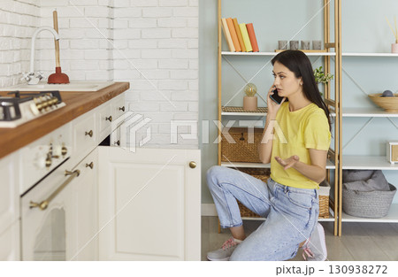 Woman calling in plumbing service as has problem with sink, using plunger Woman calling in plumbing service as has problem with sink, using plunger 130938272