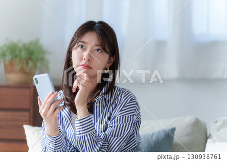 スマホを持って考える若い女性 130938761