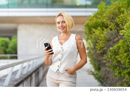 Smiling young blond businesswoman using smartphone Smiling young blond businesswoman using smartphone 130939054