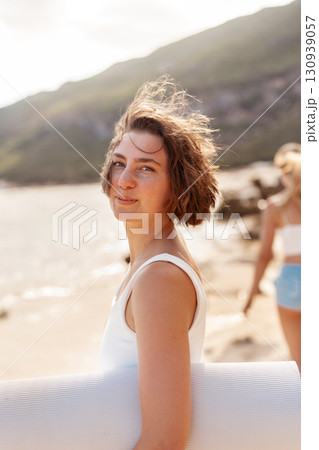 Young woman holding surfboard and looking at 130939057