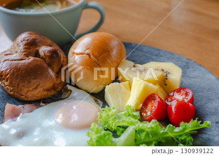 パンと目玉焼きと果物の洋風朝食 130939122