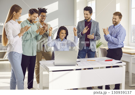 Business colleagues celebrating success looking at notebook screen 130939137