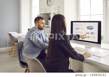 Two businesspeople analyzing data charts, graphs on pc monitor 130939141