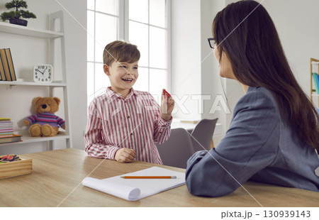 Female speech therapist with a little boy patient practicing private development lesson. Female speech therapist with a little boy patient practicing private development lesson. 130939143