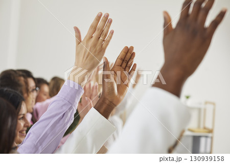 Women in audience put up their hands to ask questions after a business presentation Women in audience put up their hands to ask questions after a business presentation 130939158