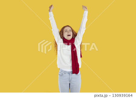 Curly readhead happy girl is rising her arms up on yellow background and looking up. 130939164