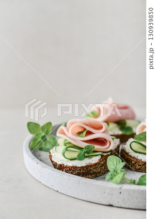 Bruschetta with baguette, bacon or meat, cream cheese, oregano and fresh cucumber Bruschetta with baguette, bacon or meat, cream cheese, oregano and fresh cucumber 130939850