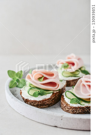 Bruschetta with baguette, bacon or meat, cream cheese, oregano and fresh cucumber 130939851