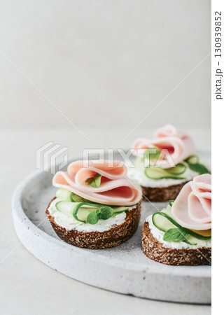 Bruschetta with baguette, bacon or meat, cream cheese, oregano and fresh cucumber 130939852