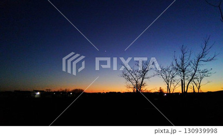 夕暮れの空に輝く一番星とシルエットの木々 130939998