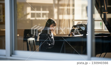 望遠レンズで校舎外から窓越しに撮影した、音楽室でピアノを弾く女子高校生 望遠レンズで校舎外から窓越しに撮影した、音楽室でピアノを弾く女子高校生 130940366