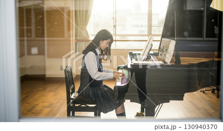 望遠レンズで校舎外から窓越しに撮影した、音楽室でピアノを弾く女子高校生 130940370