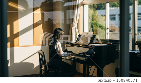 望遠レンズで校舎外から窓越しに撮影した、音楽室でピアノを弾く女子高校生 130940371