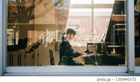 望遠レンズで校舎外から窓越しに撮影した、音楽室でピアノを弾く女子高校生 130940372