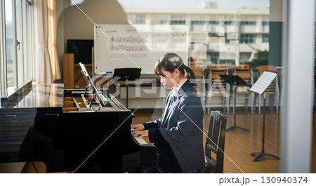 望遠レンズで校舎外から窓越しに撮影した、音楽室でピアノを弾く女子高校生 130940374